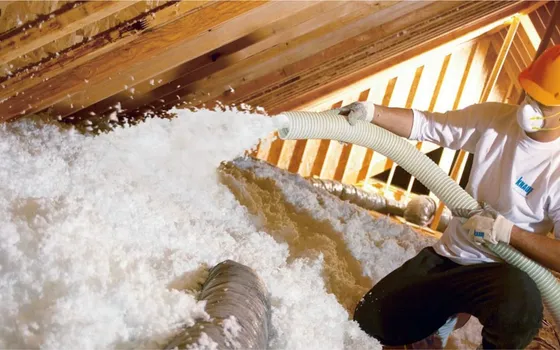 Installer blowing loose-fill insulation across an attic floor